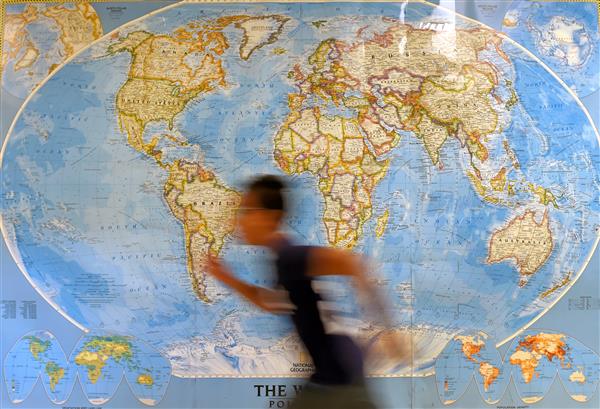 Student running in front of a world map Student running in front of a world map